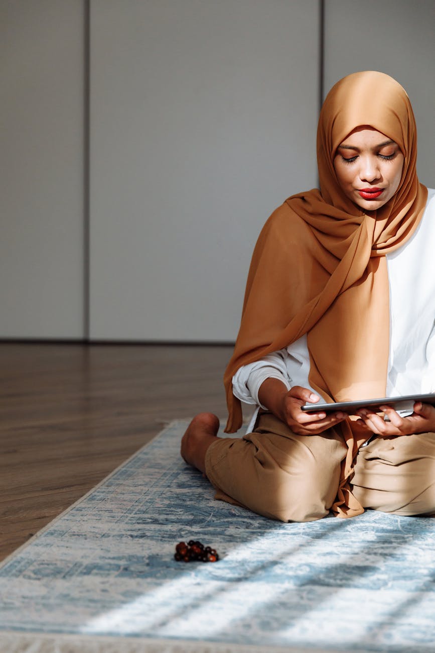 woman in brown hijab looking at a tablet